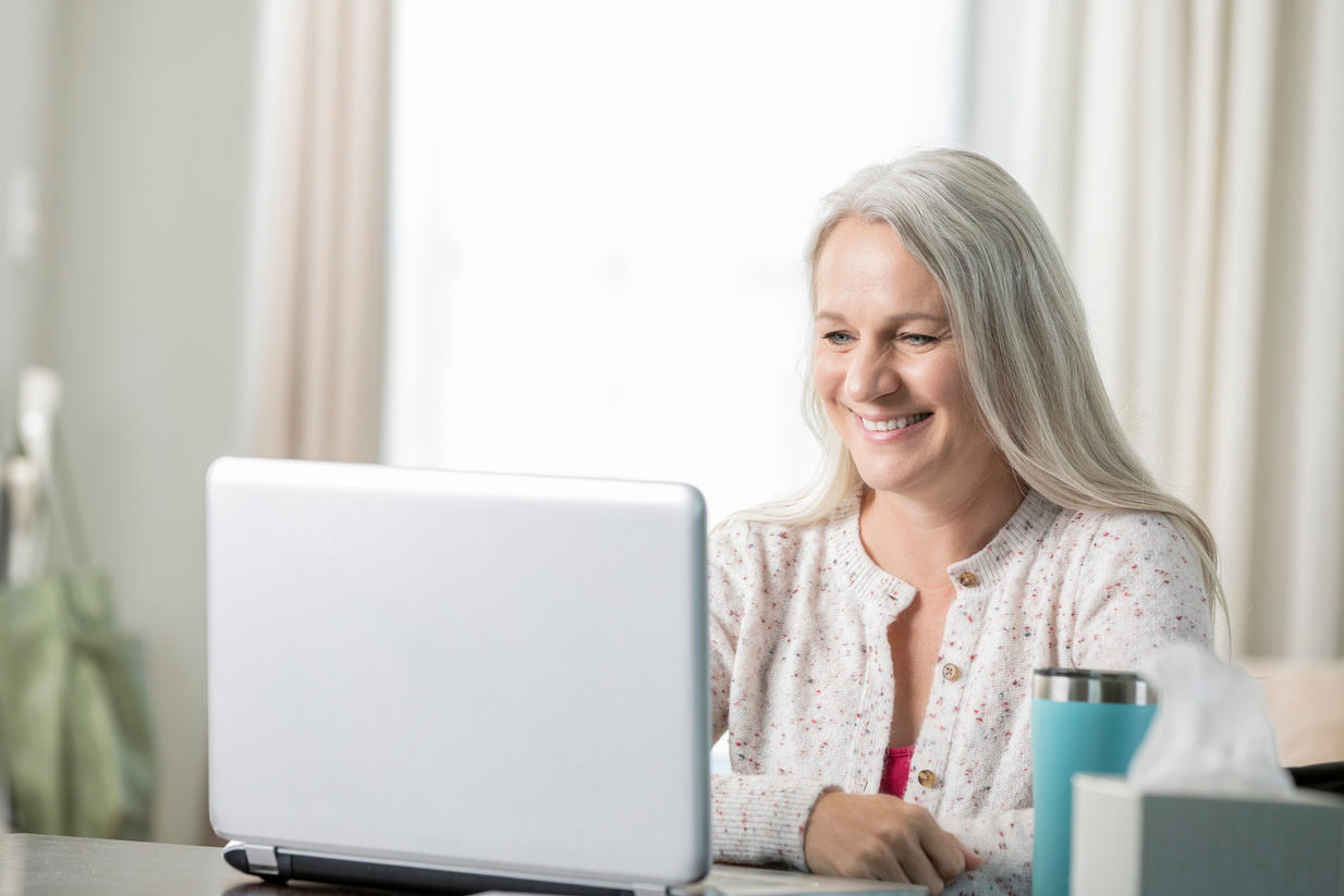 Senior woman smiles while discussing health with doctor during telehealth appointment